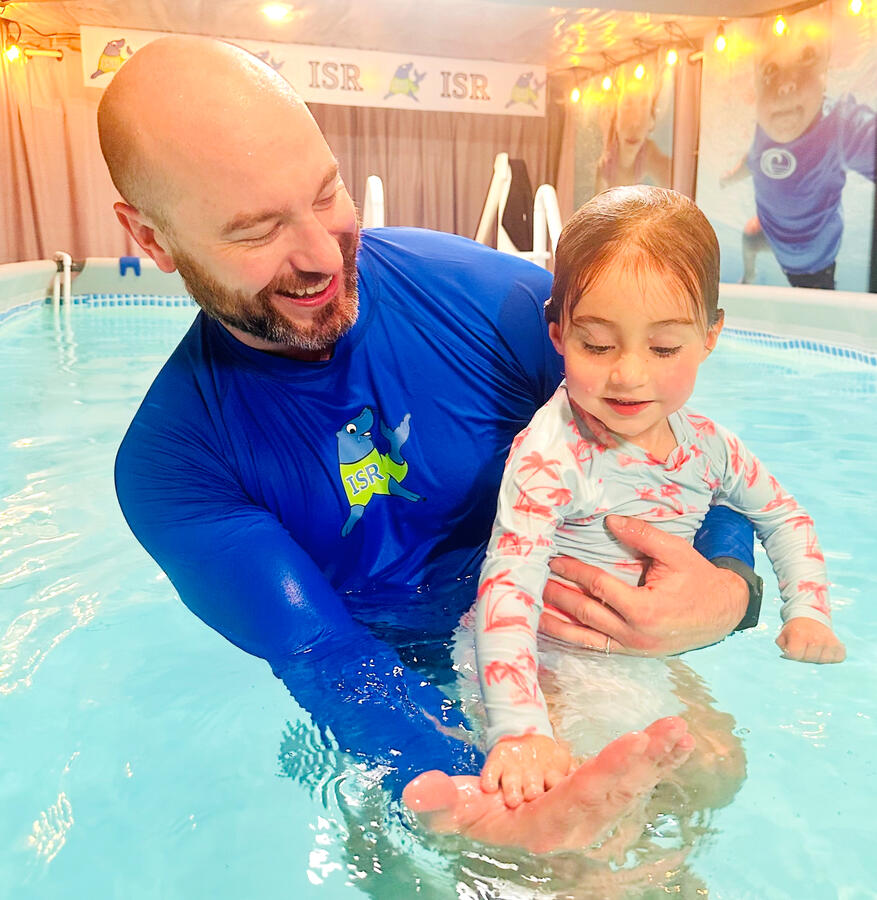 Man giving a child a high five in a pool.